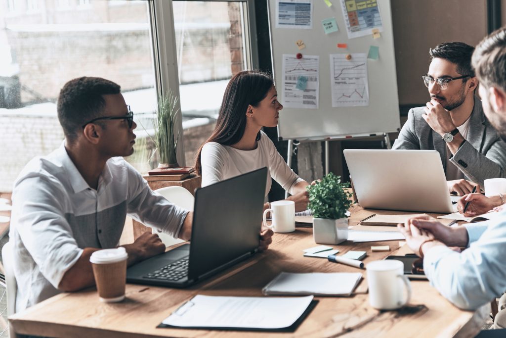 Successful business team. Group of young modern people in smart casual wear discussing business while sitting in the creative office